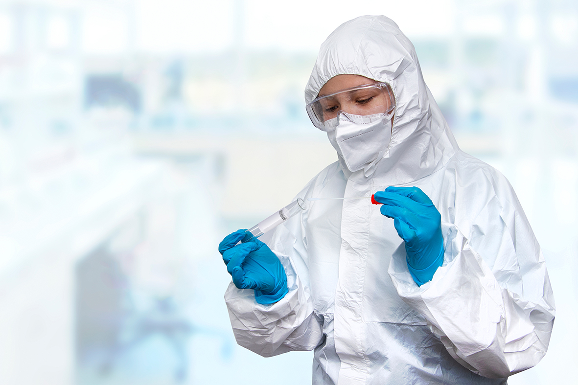 Person in PPE equipment opening a test tube
